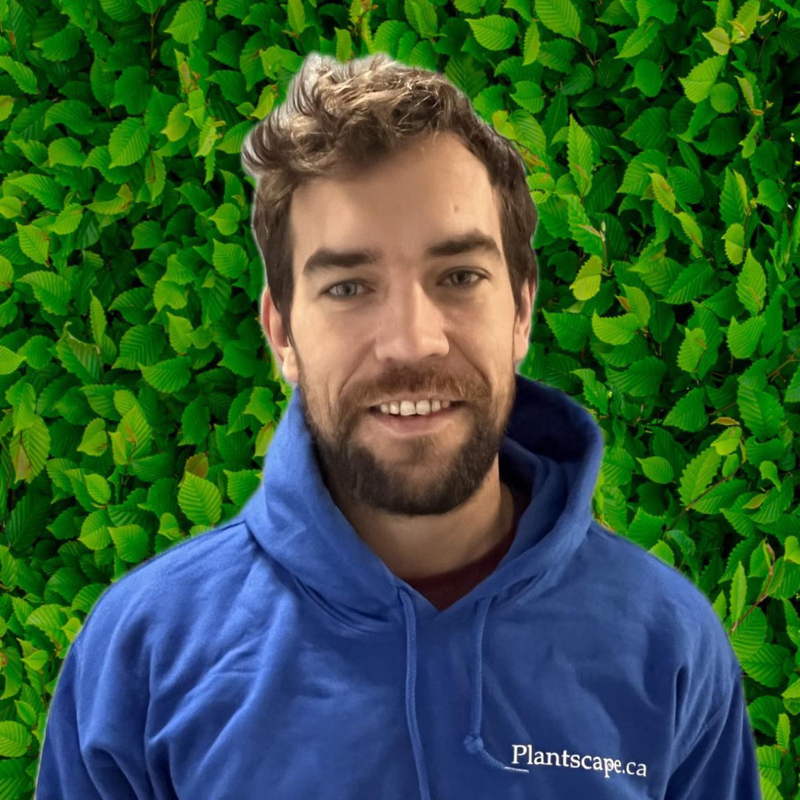 A person with a beard is smiling in front of a green leafy background, wearing a blue hoodie with the text "Plantscape.ca" printed on it.